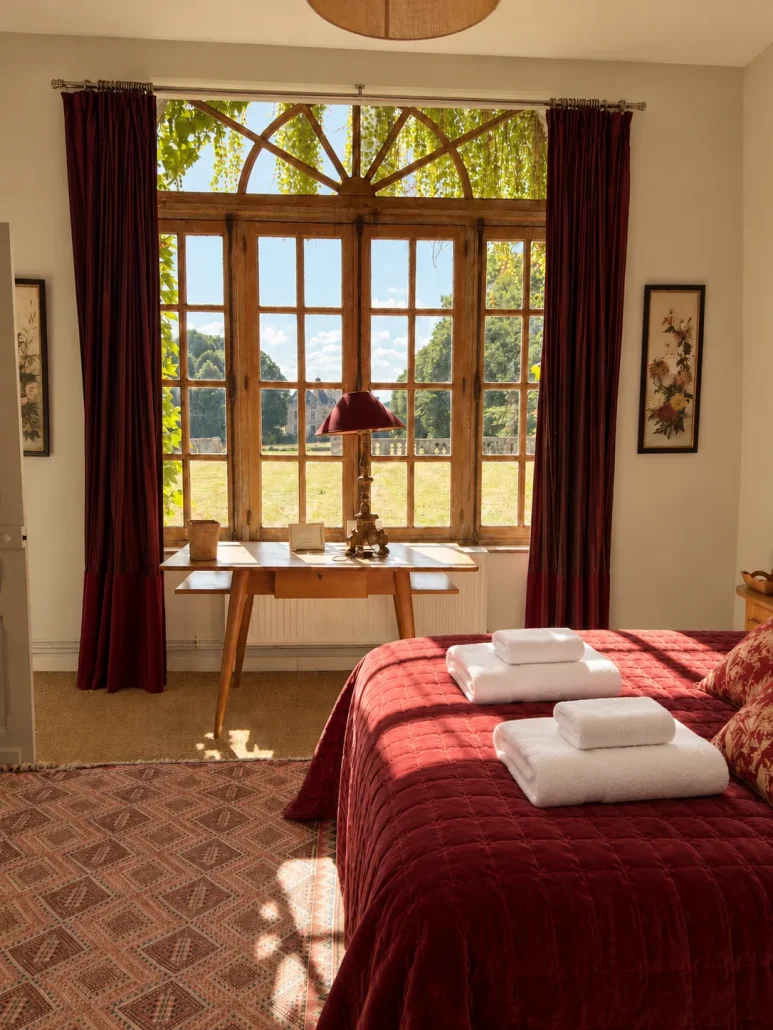 Chambre rouge de l'orangerie avec bureau près des fenêtres